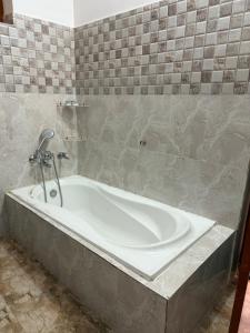 a bath tub in a bathroom with a tile wall at Colonel Cottage in Prayagraj