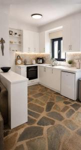 a kitchen with white cabinets and a stone floor at VILLA MIPA Samos in Kámpos
