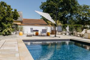 a swimming pool with an umbrella and two chairs and a patio at Ferienwohnungen Proschahaus in Eisenberg an der Pinka