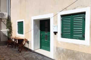 a building with green doors and a table and chairs at Kalelarga in Betina