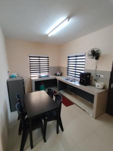 a room with a table and a desk and two windows at Homestay Che Wan Satu in Kuantan