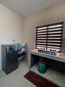 a kitchen with a refrigerator and a table and a window at Homestay Che Wan Satu in Kuantan +7 photos