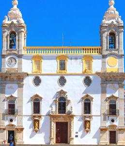 a large white building with a clock on it at La Petite Piété in Faro