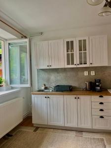 a kitchen with white cabinets and a sink and a window at Domček u Ferka in Dedinky