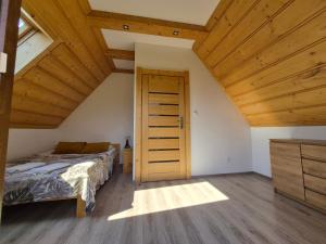 a bedroom with a bed and a wooden ceiling at NowiNowe Domki in Dzianisz