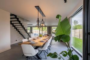 a dining room with a long wooden table and white chairs at Het Meer in Rotselaar