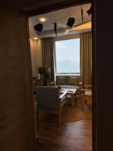 a living room with a table and a couch and a window at The Second Home , Chamba Hills in Chamba