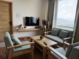 a living room with a couch and a table and a tv at The Second Home , Chamba Hills in Chamba