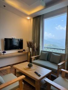 a living room with a couch and a large window at The Second Home , Chamba Hills in Chamba