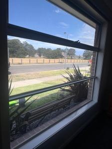 a window with a view of a street and a plant at Park Views Guest Room in Kilmore