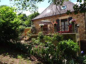 a house with a balcony with flowers and an umbrella at Domaine de La Bessade in Le Bugue