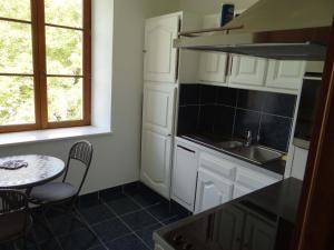 a kitchen with white cabinets and a table and a sink at Domaine de La Bessade in Le Bugue