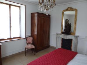 a bedroom with a bed and a mirror and a chair at Domaine de La Bessade in Le Bugue