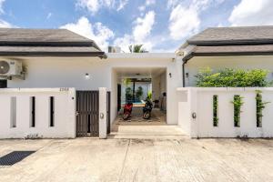 a white house with a motorcycle parked in the driveway at Private pool villa in Kamala Beach