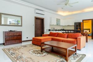 a living room with an orange couch and a table at Private pool villa in Kamala Beach