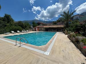 a large swimming pool with chairs and a house at Ünlü Otel in Fethiye
