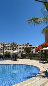 a swimming pool with chairs and umbrellas and a building at Marina Valley مارينا فالي in El Alamein