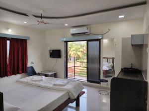 a bedroom with a bed and a large window at Bliss Paradise Resort in Malvan