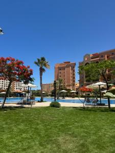 a pool with tables and umbrellas in a park at Marina Valley مارينا فالي in El Alamein
