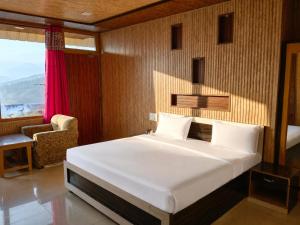 a bedroom with a bed and a chair in a room at Sherjang Events in Munsyari