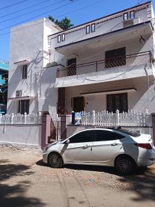 a white car parked in front of a white building at Saimithra Riverview Homestay in Tirunelveli