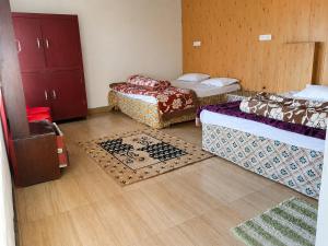 a room with two beds and two rugs on the floor at Sherjang Events in Munsyari +8 photos