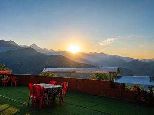 a table and chairs on a balcony with a view of mountains at Sherjang Events in Munsyari