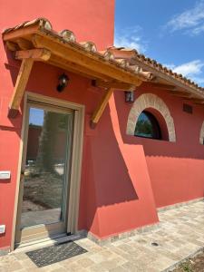 a red building with a door and a window at Fattoria solidale del Circeo in Pontinia