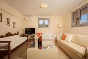 a living room with white couches and a tv at Villa Maragoudi in Arménoi