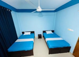 two beds in a room with blue walls at RL Holiday Inn in Jaffna