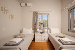 two twin beds in a room with a window at Villa Maragoudi in Arménoi +52 photos