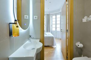 a bathroom with a sink and a mirror and a bed at Hostal Zahara in Ferrol