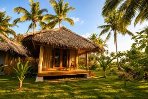 a small hut with a thatched roof on a lawn with palm trees at Akar Mentawai in Simpatdegat