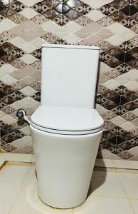 a white toilet in a bathroom with a tile wall at RL Holiday Inn in Jaffna