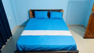 a bed in a room with blue walls and blue pillows at RL Holiday Inn in Jaffna +1 photo