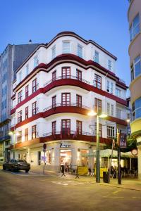 a large white building with red balconies on a street at Hostal Zahara in Ferrol