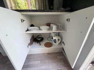 a small kitchen with white shelves with dishes on them at Raet Camping in Færvik