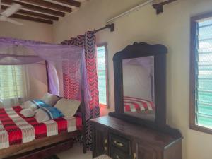 a bedroom with a bed with a mirror and a dresser at Shalma House in Lamu