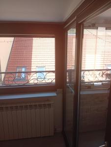an empty room with two windows and a balcony at Apartman DALIAROSE Sarajevo in Sarajevo