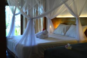 a bedroom with a canopy bed with white drapes at Akar Mentawai in Simpatdegat