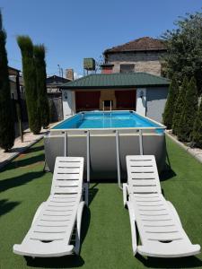 two white lounge chairs and a swimming pool at Villa Cypress in Kutaisi