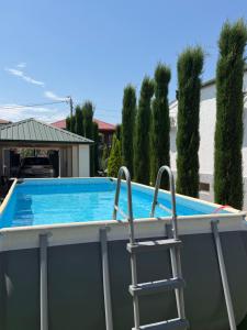a swimming pool with a ladder and a chair at Villa Cypress in Kutaisi