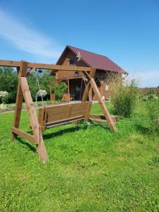 a wooden swing set in the grass in front of a house at Przytulisko in Smołdzino