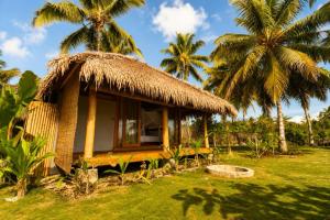 a small hut with palm trees in a field at Akar Mentawai in Simpatdegat