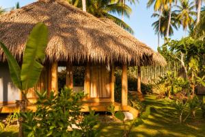 a small hut with a thatched roof and palm trees at Akar Mentawai in Simpatdegat +4 photos