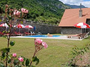 a swimming pool with tables and umbrellas in a yard at Kulla e Andrrave in Ducaj