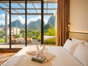 a hotel room with a bed with a view of mountains at Yulong River Scenic Area,Floor-to-ceiling Windows for viewing,Swimming Pool & Coffee & Butler Service,10 minutes by car from West Street in Yangshuo