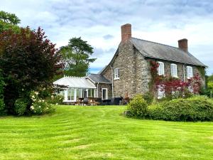 an old stone house with a grass yard at Mid-Wales Farmhouse, swimming pool, tranquil countryside views, sleeps 14 in Meifod