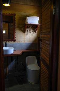 a small bathroom with a toilet and a sink at Tiger Track Eco Lodge in Bardiyā