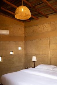 a bedroom with a white bed and a lamp at Tiger Track Eco Lodge in Bardiyā